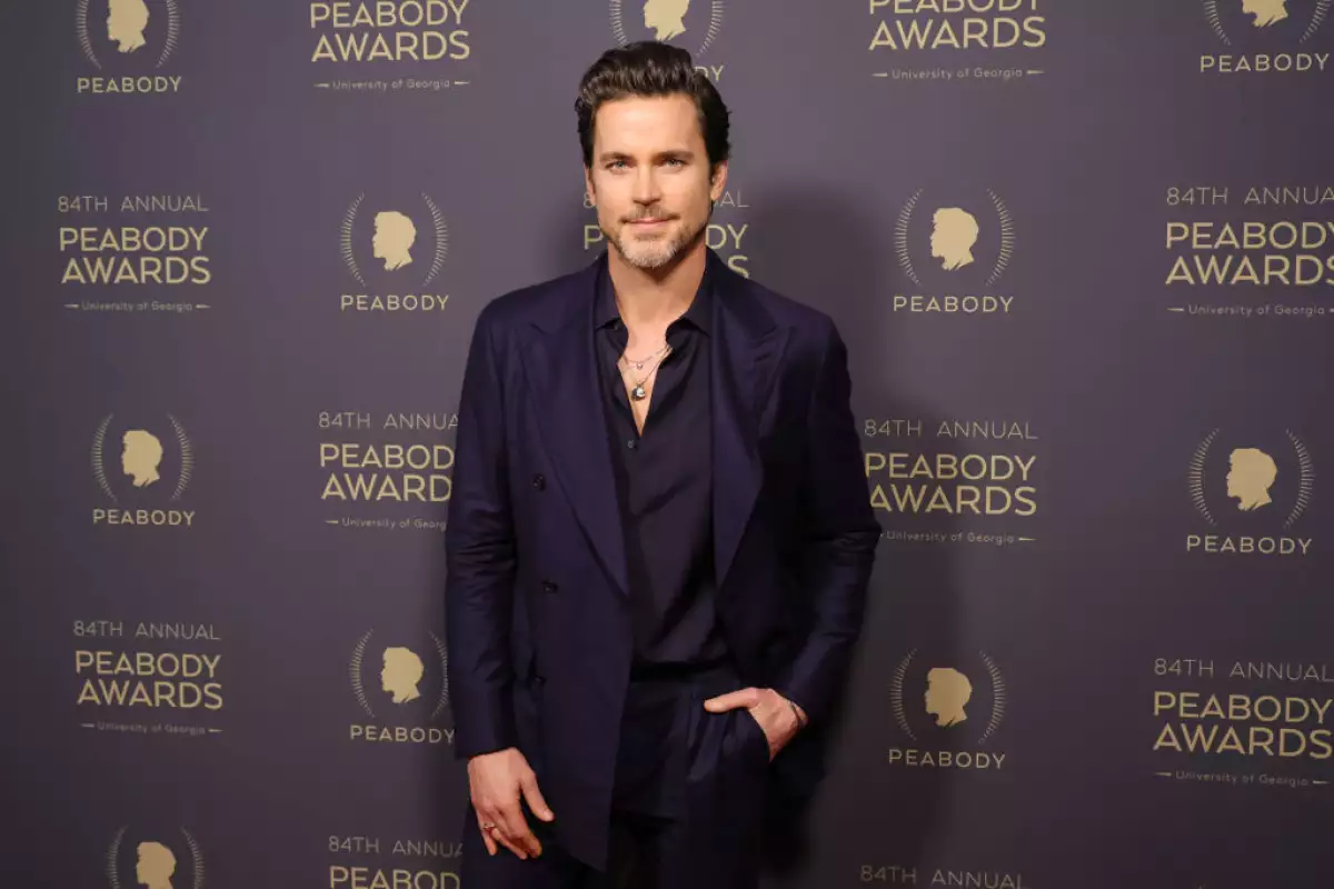 Matt Bomer en los Peabody Awards vistiendo un traje oscuro y una camisa negra desabotonada.