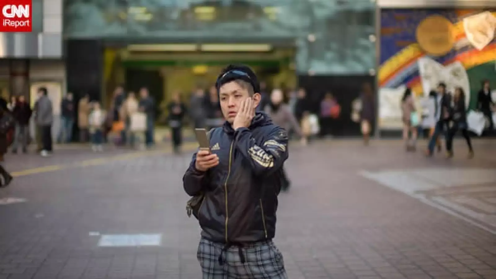 un joven ve su celular en tokio