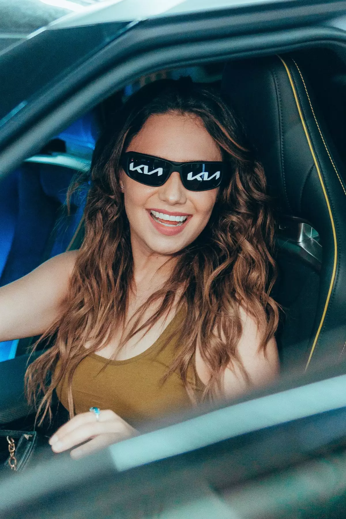 Una mujer está arriba de un auto Kia, en el stand de la marca en el Tecate Emblema