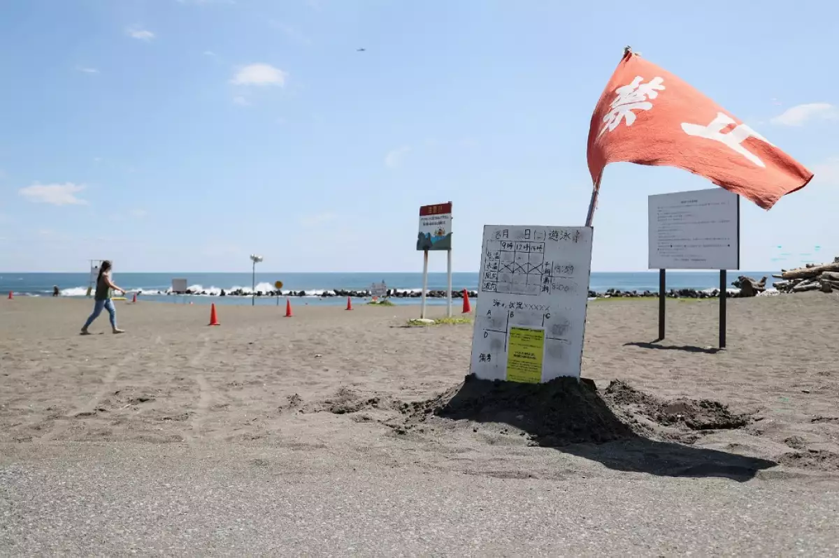 Una bandera roja ondea en el viento mientras las autoridades advierten contra la natación en el parque de la playa Shonan Bellmare Hiratsuka en Hiratsuka, prefectura de Kanagawa, al suroeste de Tokio, el 10 de agosto de 2024, después de que la ciudad tomara medidas en respuesta al anuncio del gobierno de una "advertencia de gran terremoto".