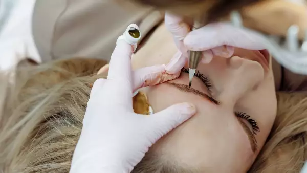 Permanent makeup, tattooing of eyebrows. Cosmetologist applying make up