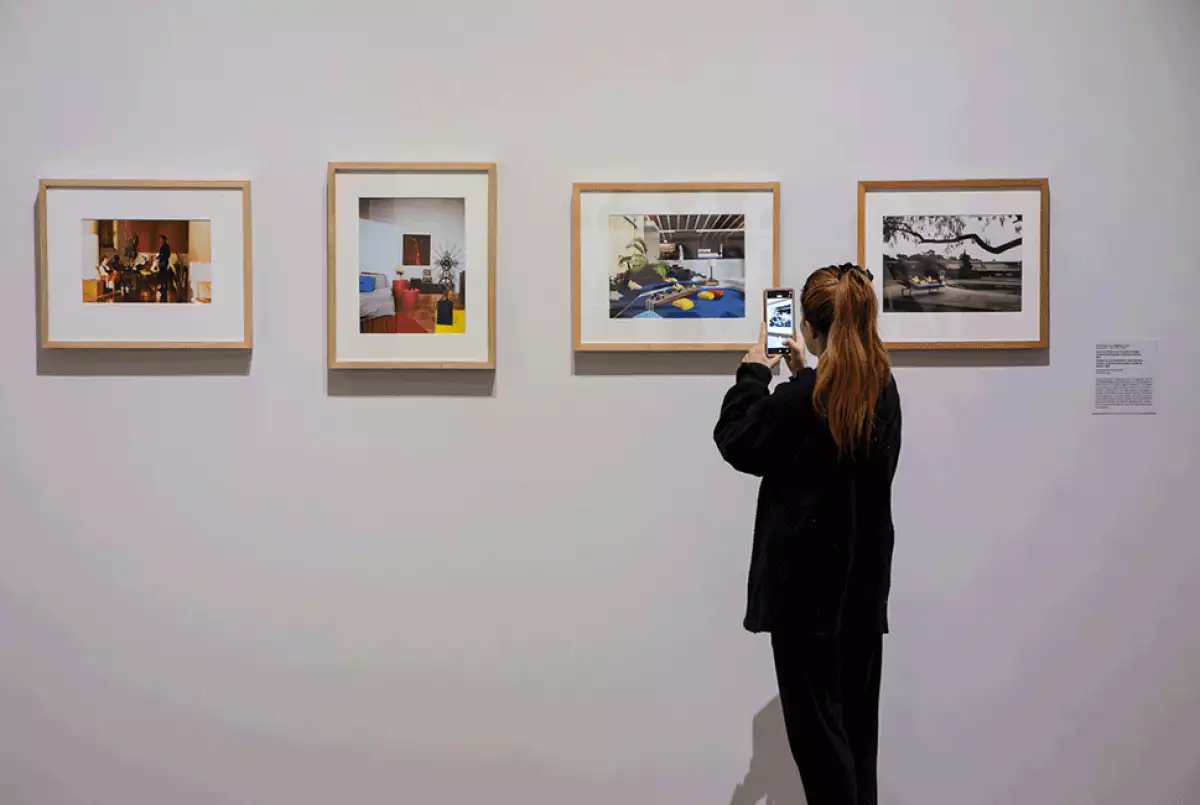 Imagen de una mujer tomando fotos a la exposición 'Mexichrome' del Palacio de Bellas Artes.