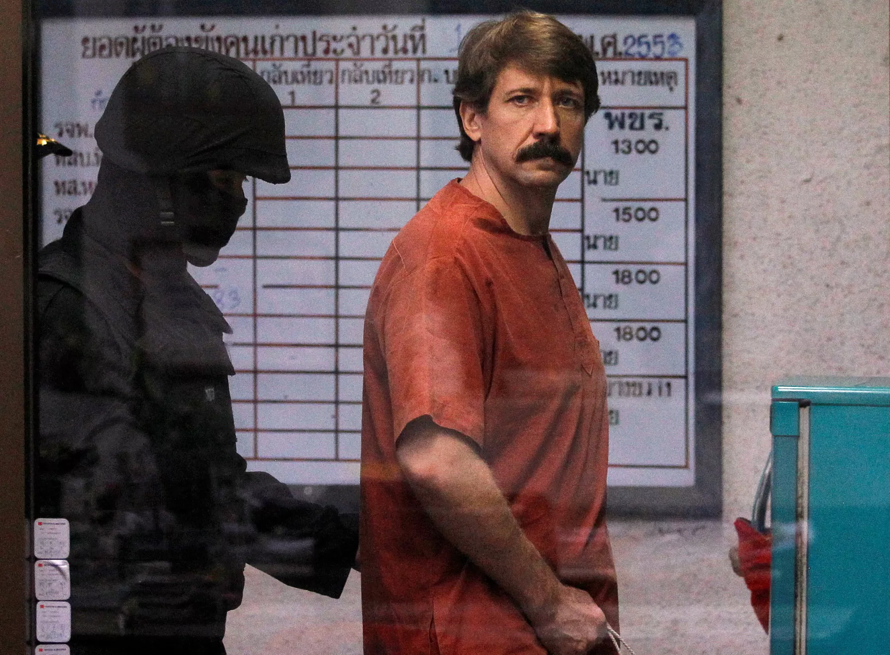 El presunto contrabandista de armas Viktor Bout de Rusia es escoltado por un miembro de la unidad especial de policía cuando llega a un tribunal penal en Bangkok, Tailandia.