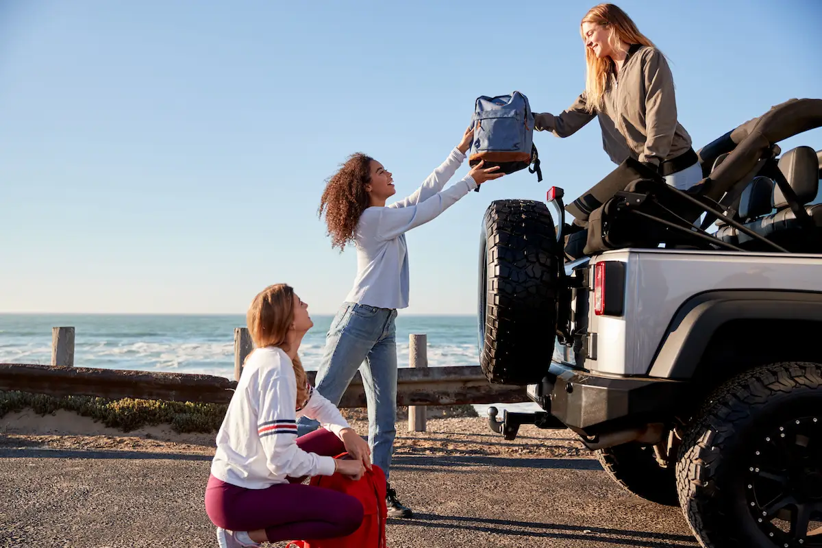 Three,Young,Adult,Girlfriends,Unloading,Backpacks,From,A,Car