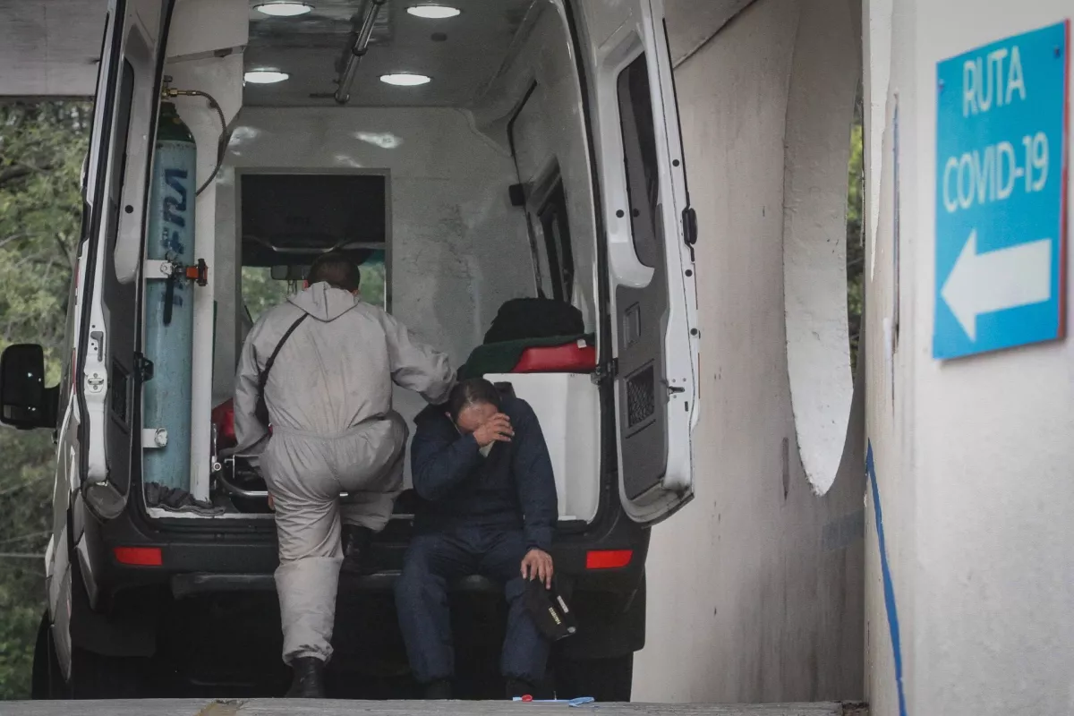 Un paramédico descansa sentado en la defensa de una ambulancia