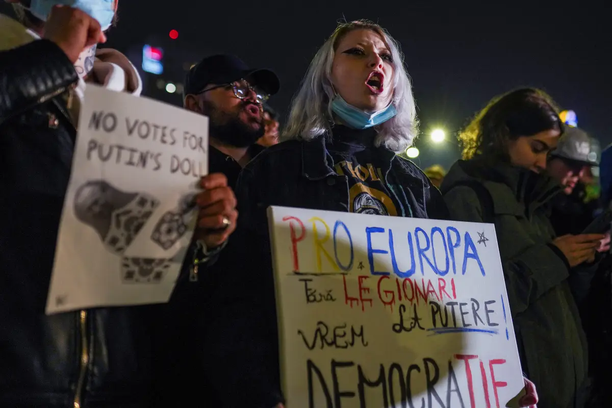 Una mujer sostiene un cartel que dice "Pro-Europa" y "Queremos democracia" mientras corea consignas durante una protesta contra Calin Georgescu, el candidato independiente a la presidencia rumana que llegó a la es elecciones, en Bucarest, Rumania, el 27 de noviembre de 2024.