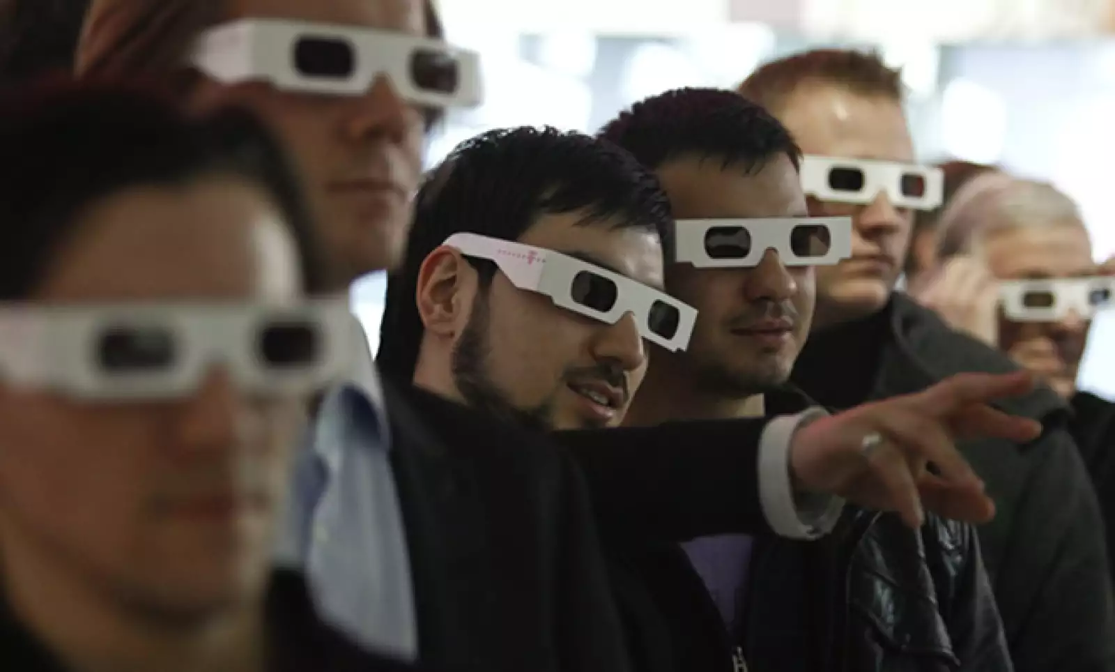 Varias personas utilizan lentes de 3-D para ver la presentación de Deutsche Telekom.