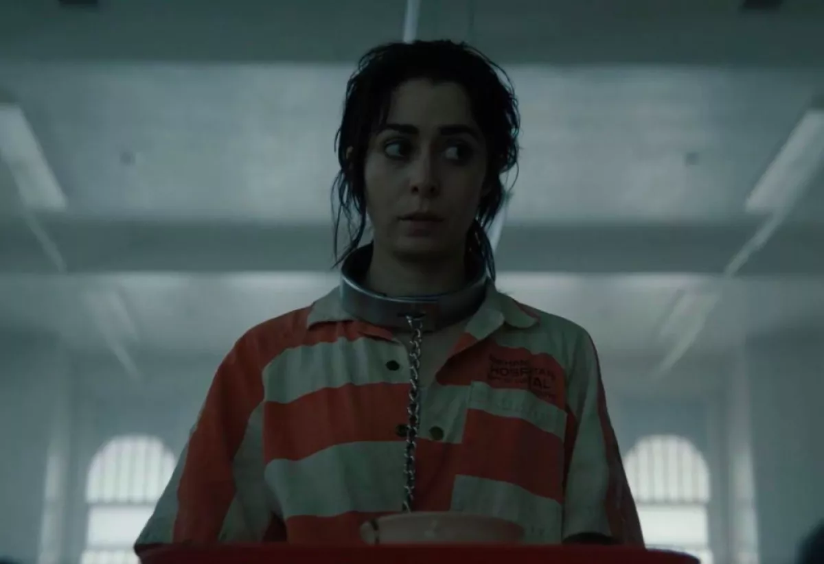 Foto de una escena de El Pingüino que muestra a Sofía Falcone con traje de interna de psiquiátrico (rayas anaranjadas y blancas) y una cadena en el cuello.
