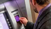 Hombre sacando dinero de un cajero automático con su tarjeta Nu.