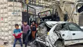 Los niños palestinos caminan cerca de un coche dañado después de una incursión israelí, en Tulkarm, en la Cisjordania ocupada por Israel, el 17 de diciembre de 2023.