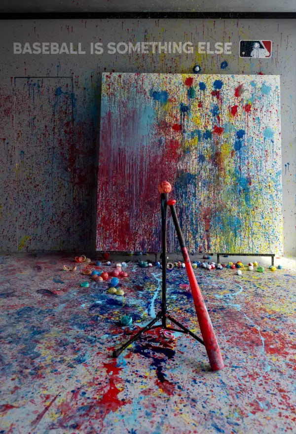 Foto de una exhibición de arte con pintura regada por todo el cuarto y un bat y una pelota de beisbol.