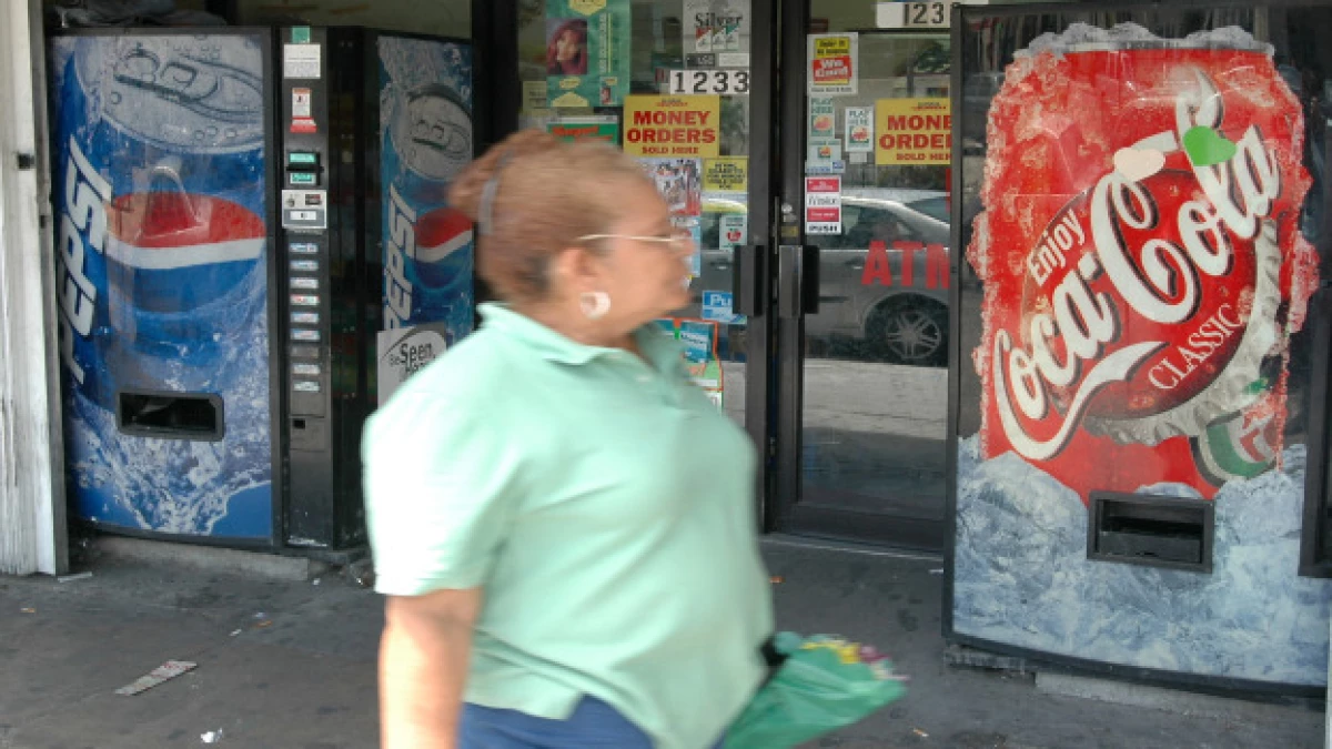 una mujer mira las máquinas de Pepsi y Coca