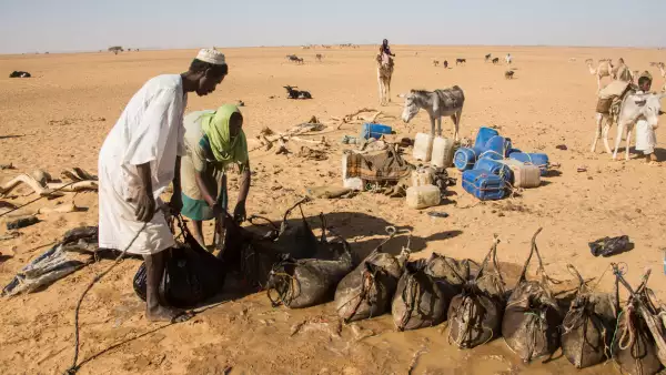 Karima, Sudán - 6 de enero de 2011: Los nómadas llenan sus sacos de agua en una fuente profunda en el desierto, Sudán