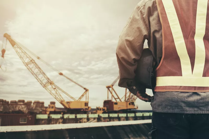 construction worker checking location site with crane on the background