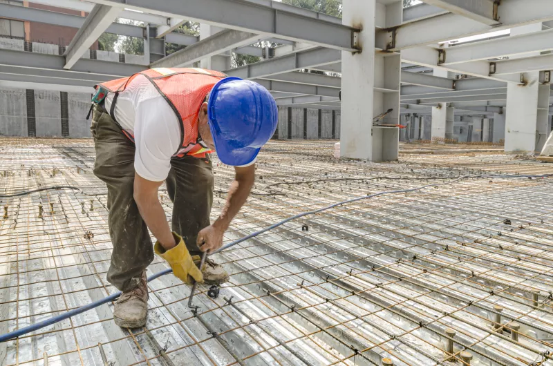 Construction worker tightening the iron mesh rods to steel plates