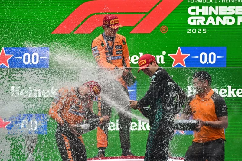 El ganador, el piloto australiano de McLaren, Oscar Piastri (arriba), celebra con el segundo lugar, el piloto británico de McLaren, Lando Norris (izquierda inferior) y el tercer piloto británico de Mercedes, George Russell (segundo a la derecha) en el podio después del Gran Premio de China de Fórmula Uno en el Circuito Internacional de Shanghai en Shanghái el 23 de marzo de 2025.