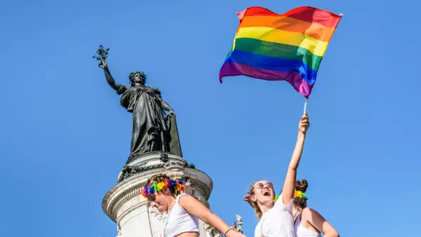 A young woman waves a rainbow flag high during the Gay Pride parade in Paris, France.