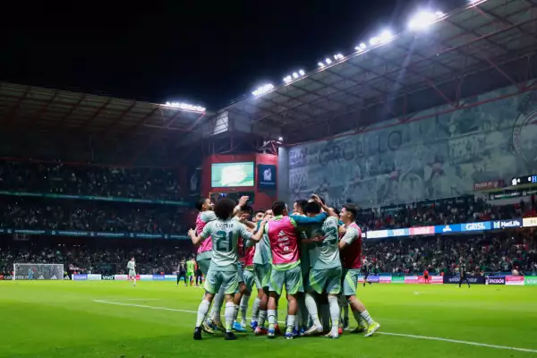 Foto de la selección mexicana de futbol en el campo de juego abrazándose al celebrar un gol contra Honduras.