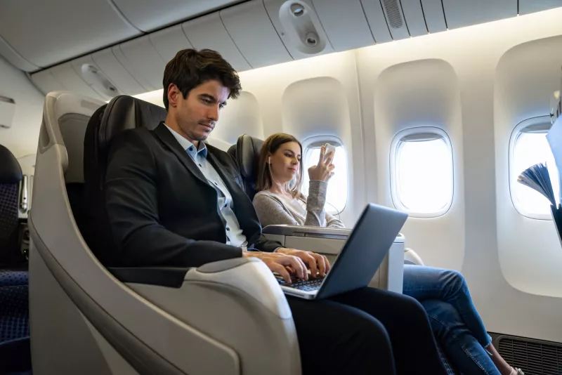 Business man traveling by plane and working on his laptop
