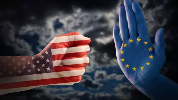 trade conflict, fist with USA flag against a hand with European flag, dramatic cloudy sky in the background