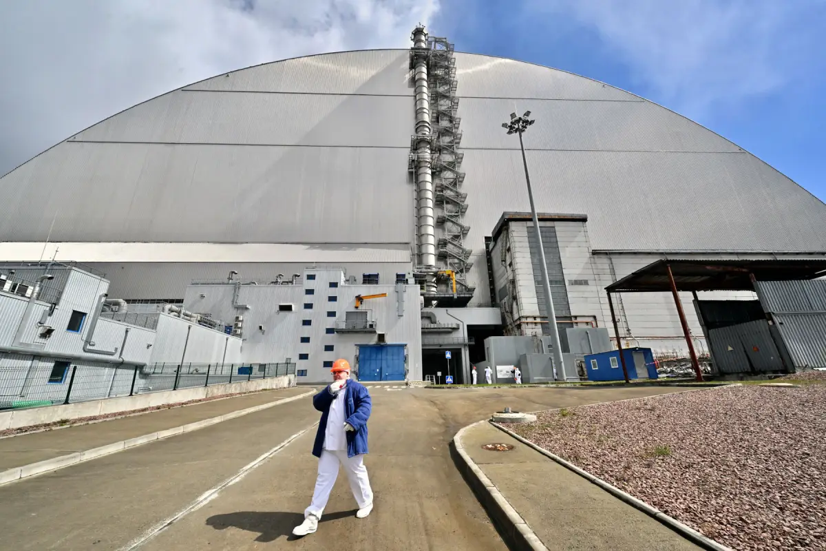 Un empleado pasa por el Nuevo Confinamiento Seguro (NSC), cubriendo el cuarto reactor destruido en la Planta de Energía Nuclear de Chernobyl el 23 de abril de 2026.