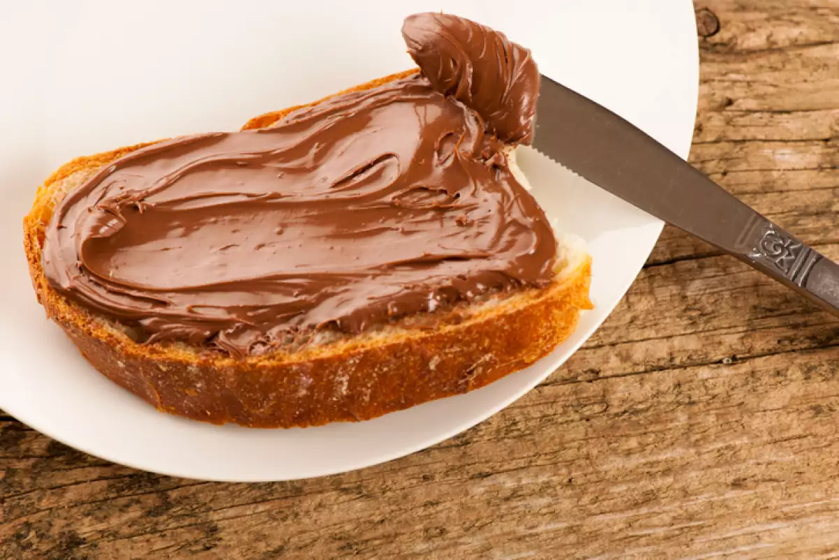 Slice of bread with sweet chocolate nougat spread white plate