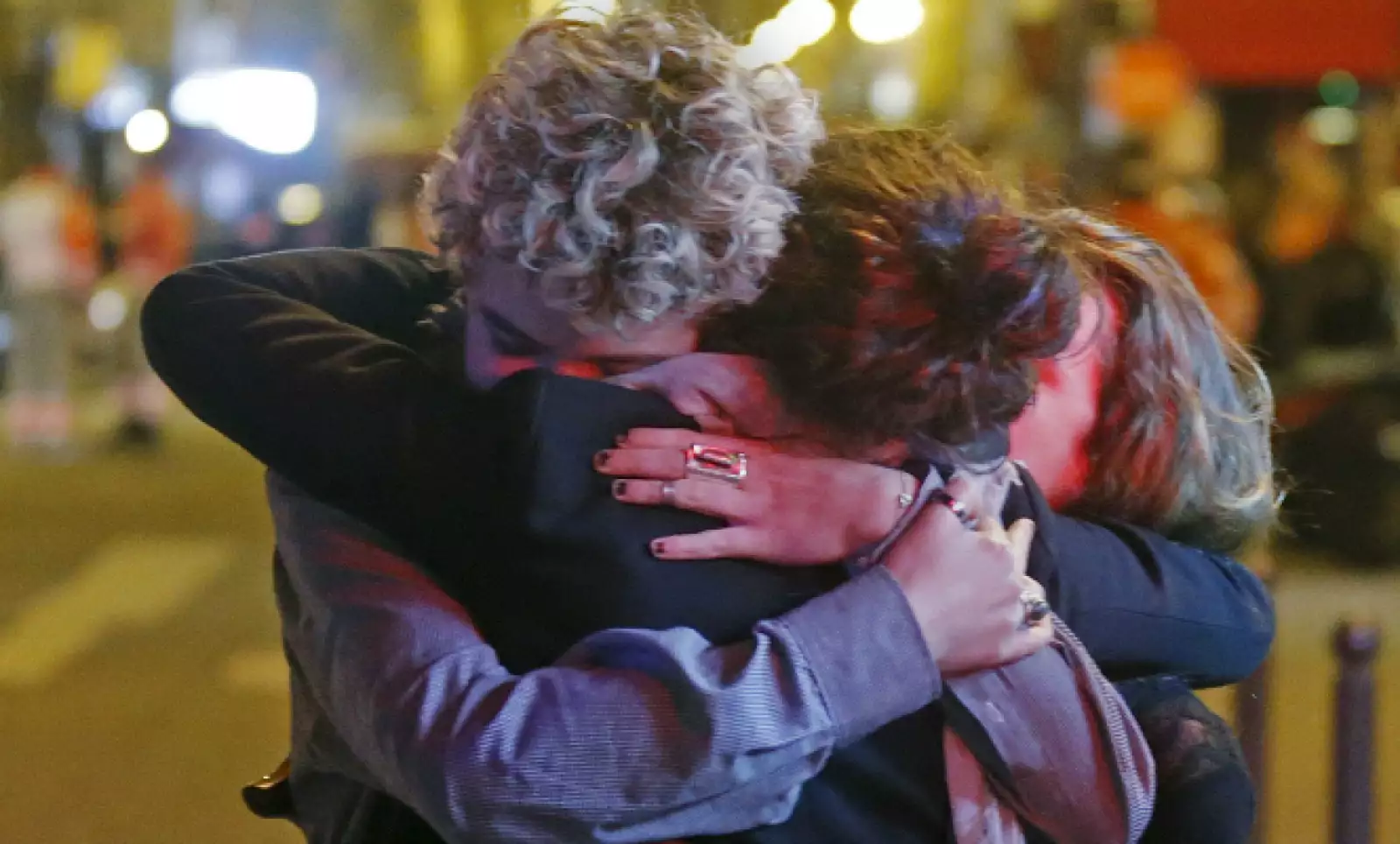 Un grupo de personas se abrazan al salir del teatro en el que más de 100 personas murieron.