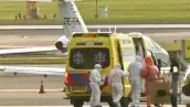 Una ambulancia que transporta a una persona contagiada por hantavirus en un crucero, alrededor hay médicos con trajes especiales de protección. 