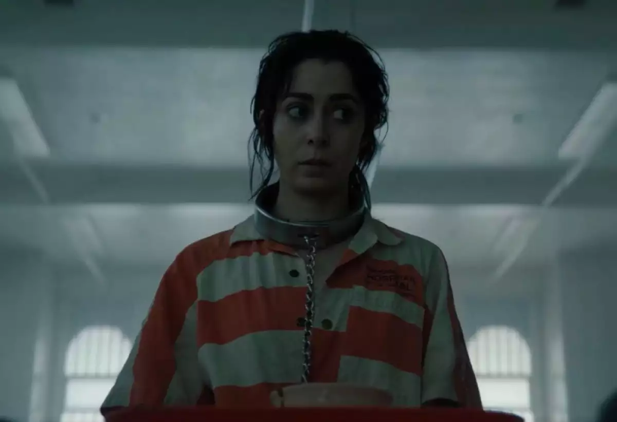 Foto de una escena de El Pingüino que muestra a Sofía Falcone con traje de interna de psiquiátrico (rayas anaranjadas y blancas) y una cadena en el cuello.