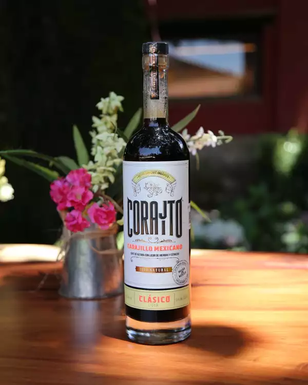 Botella de Corajito en una mesa con flores