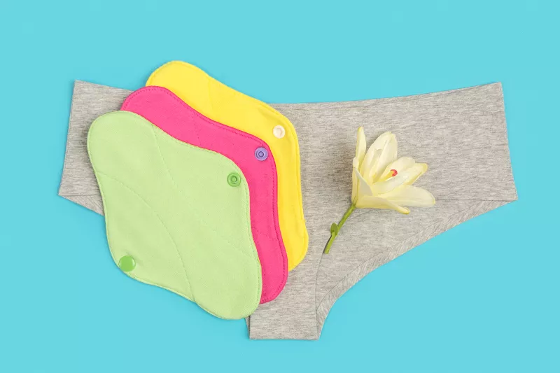 Colored eco reusable menstrual pads and grey panties on blue background. Health care and zero-waste, no plastic concept. Top view Flat lay Close-up