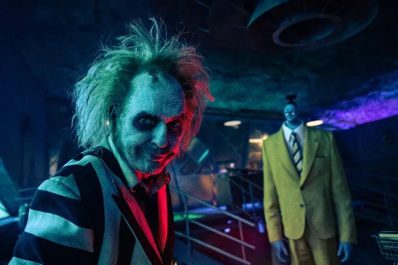 Foto de una escena de la película Beetlejuice 2 donde se ve a Michael Keaton viendo hacia la cámara y atrás el personaje de 'Bob'.