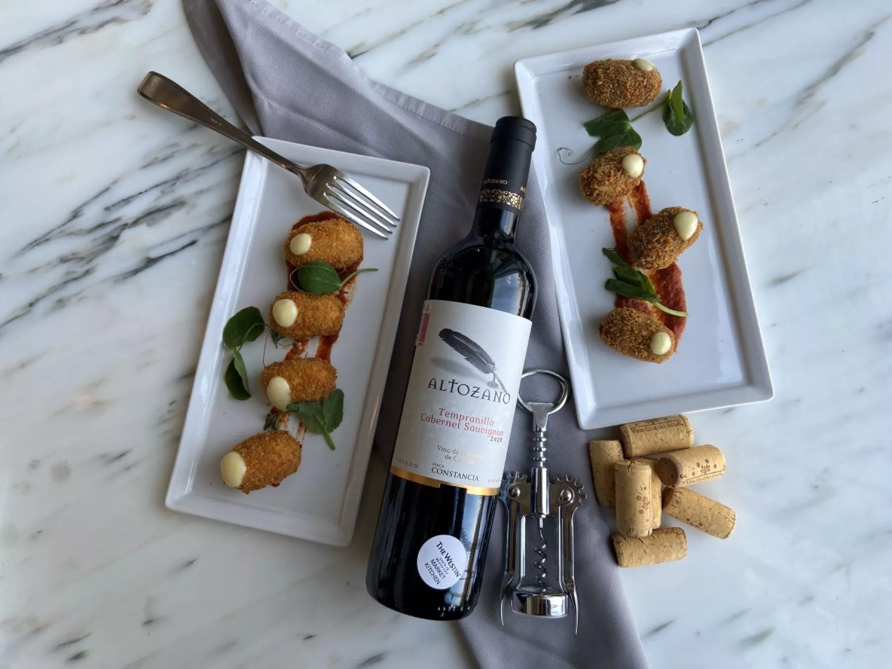 Un vino tinto sobre una mesa, con un sacacorchos a un lado y pequeñas tapas, para el Santa Fe Food & Wine Festival.