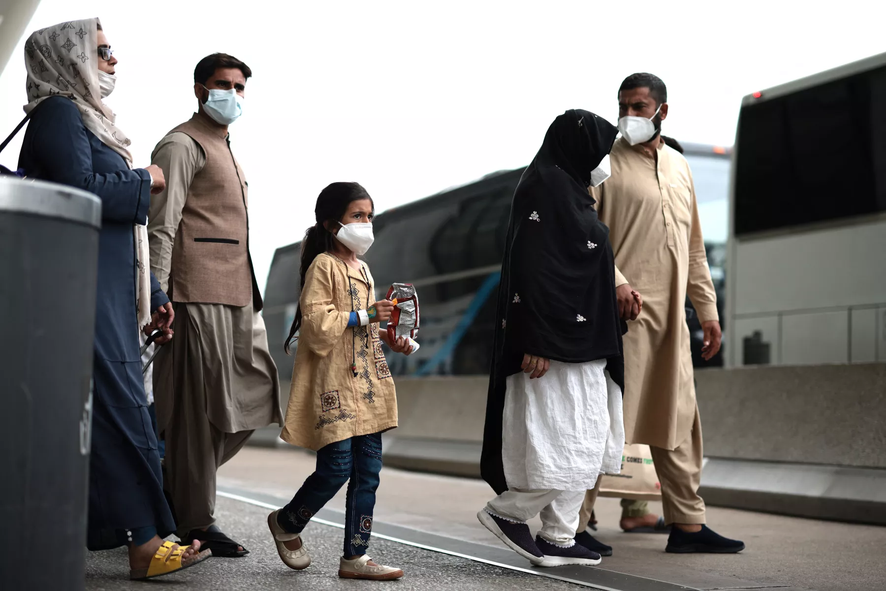 Los refugiados caminan para abordar un autobús en el aeropuerto internacional de Dulles después de ser evacuados de Kabul tras la toma de Afganistán por los talibanes.