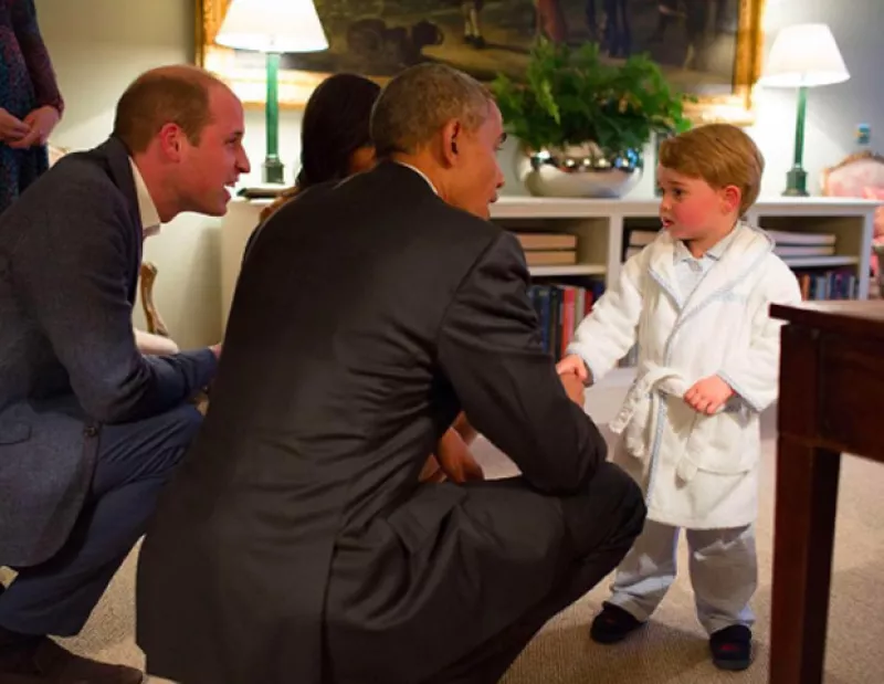 El príncipe George se vuelve la estrella del palacio de Kensington al saludar a Barack y Michelle Obama con su bata y pantuflas, momentos antes dormir.