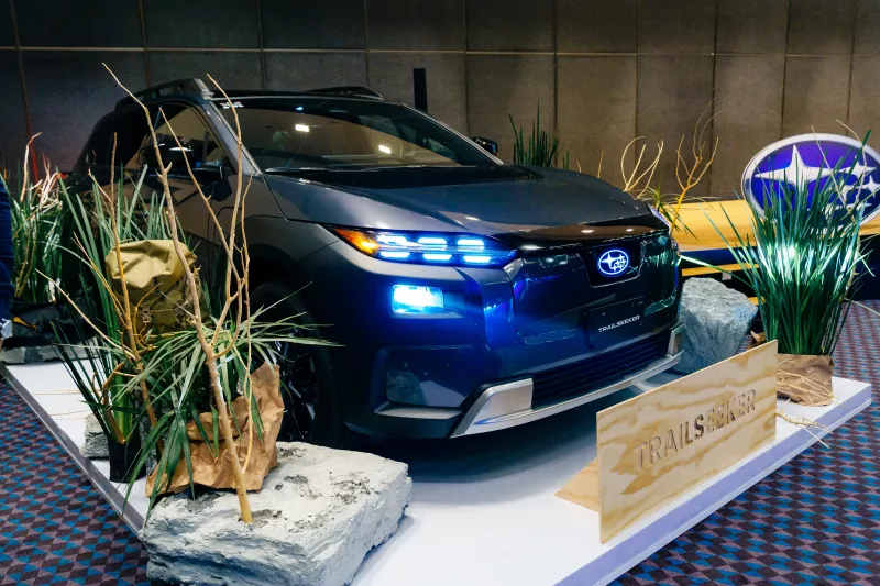 Foto del Subaru Trailseeker en el estan de presentación, con las luces encendidas, destacando el emblema de Subaru iluminado.