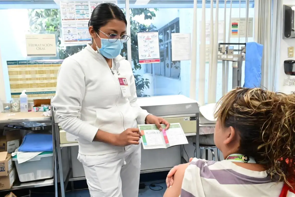 Una enfermera muestra la cartilla de vacunación a una paciente en México