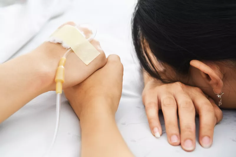 Mujer sostiene la mano de un paciente con una sonda