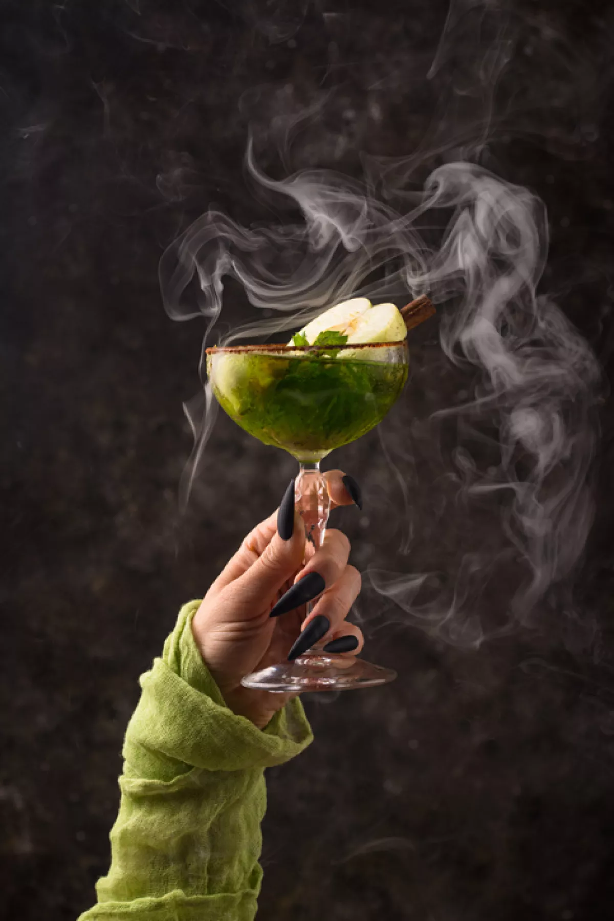 Halloween green apple cocktail with witch hand