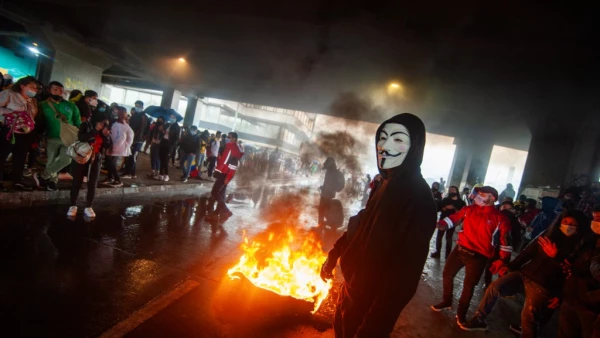 Un manifestante usando una máscara del grupo Anonymous es visto frente a un incendio en Bogotá Colombia el 28 de abril.