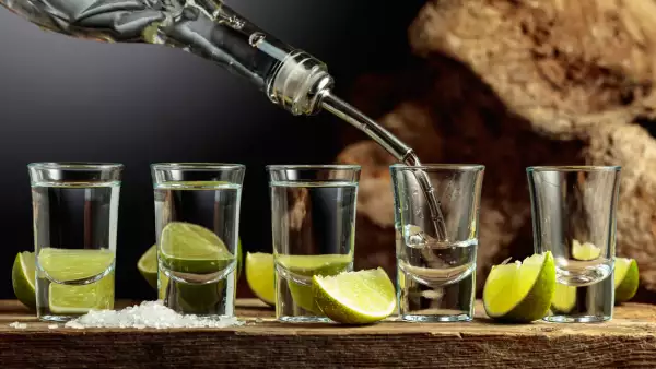 Silver Tequila with salt and lime slices on an old wooden board.