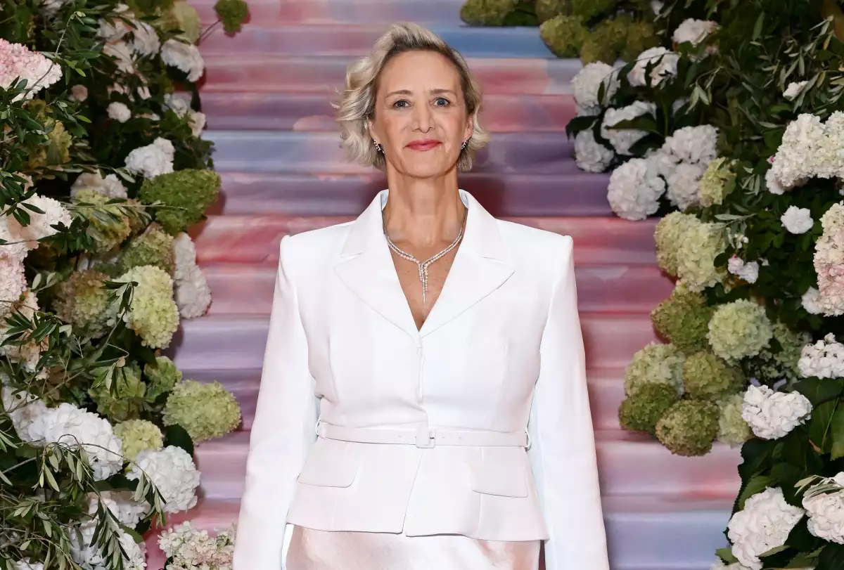 Foto de la actriz Janet McTeer con un conjunto de dos piezas color blanco posando frente a la cámara en un escenario lleno de flores.