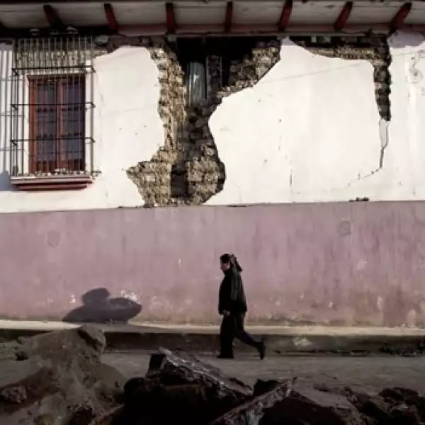 una mujer camina entre escombros