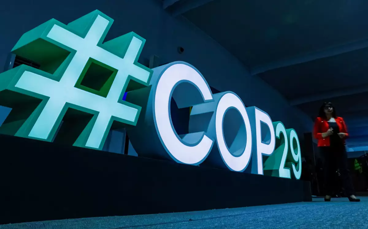 A woman passes by a #COP29 sign during the United Nations climate change conference COP29 in Baku