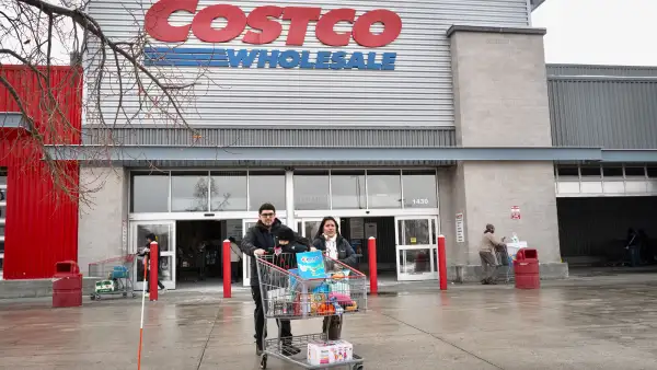 Clientes caminando con un carrito lleno fuera de Costco.