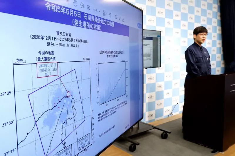 Toshihiro Shimoyama (Derecha), oficial de planificación de información sobre terremotos de la Agencia Meteorológica de Japón, habla junto a una exhibición de mapas y gráficos durante una conferencia de prensa en Tokio el 5 de mayo de 2023, después de que un terremoto de magnitud 6.5 golpeó la costa de la península de Noto en la prefectura de Ishikawa, en el centro de Japón