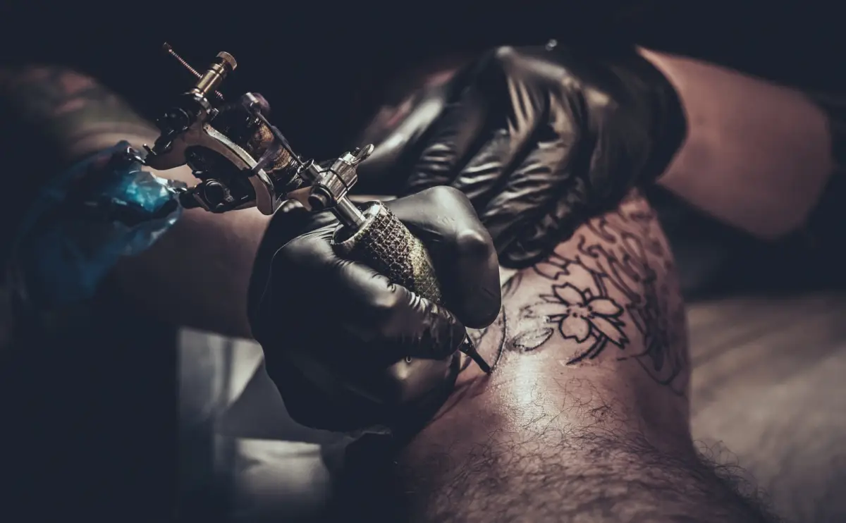 Tattoo master making tattoo on customer's leg