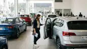 Agencia de autos seminuevos en México. Una mujer revisa una SUV para verificar las características del carro.