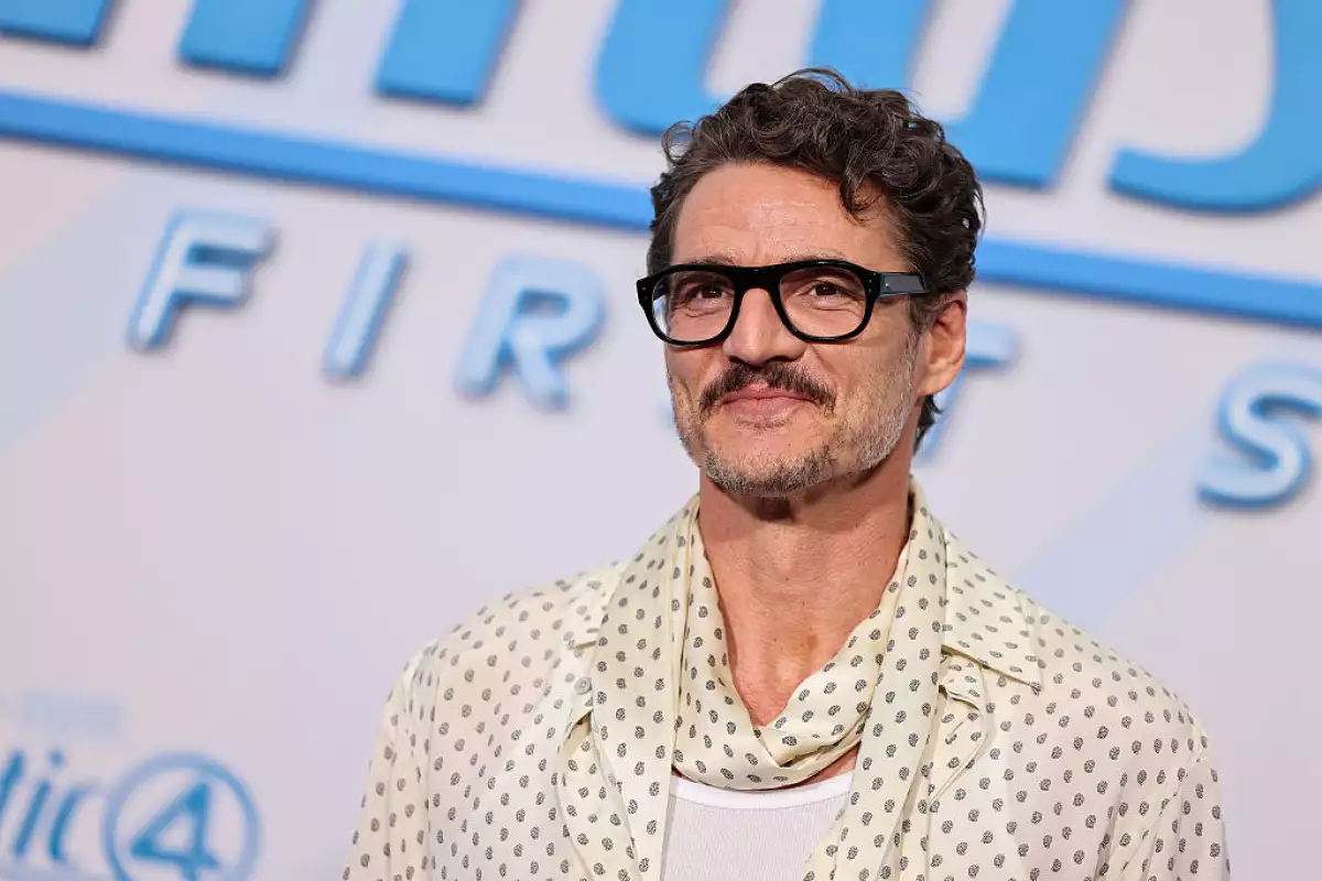 Foto de Pedro Pascal con lentes de pasta gruesa y camisa con transparencias y lunares y mascada en el cuello a juego.