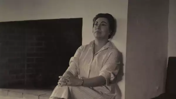 Foto en blanco y negro de Rosario Castelllanos sentada junto a una chimenea.